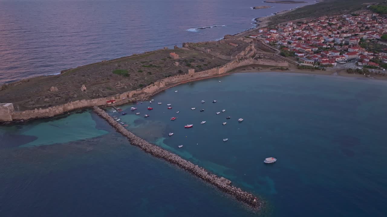 Flygfoto över Methoni slotts torn som reser sig över soluppgångens blå vatten