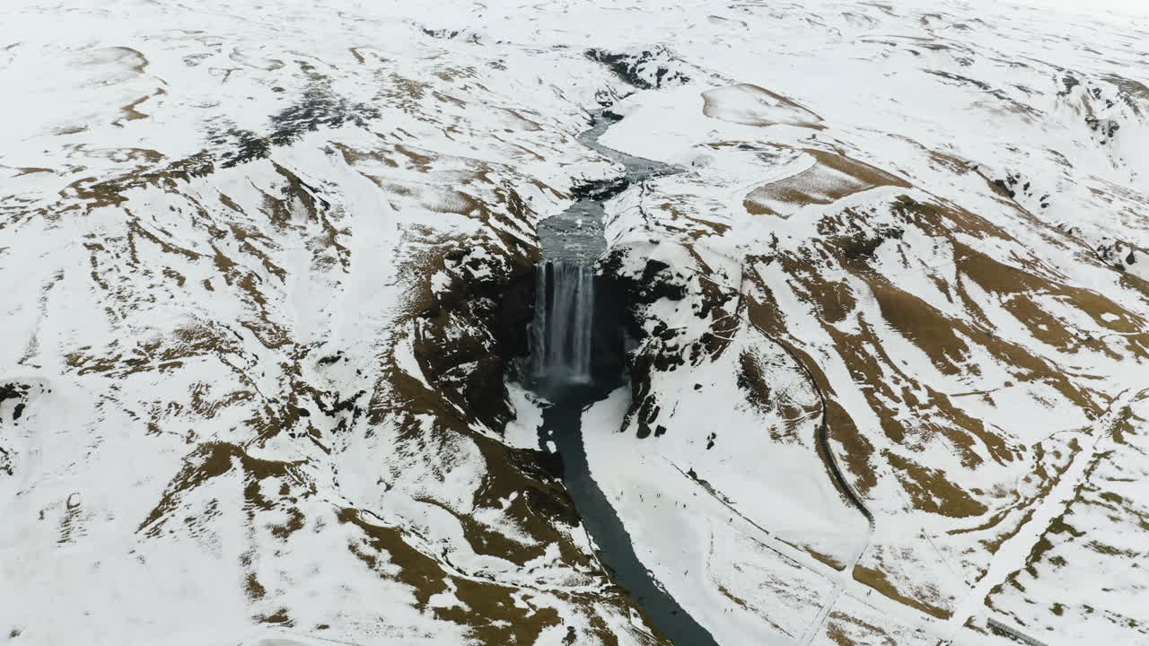 imagen de un avión no tripulado dando vueltas alrededor de la invernal cascada de skogafoss, un día nevado y nublado en islandia