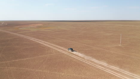 Aerial-view-of-car-driving-on-flat-track-in-the-desert