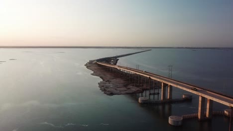 stationary aerial view of traffic on jfk memorial causeway over the gulf intercoastal waterway and laguna madre at sunset