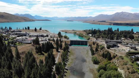 Vista-Aérea-De-Drones-Del-Pueblo-Del-Lago-Tekapo,-Presa-Y-Curso-De-Agua-Del-Río,-Nueva-Zelanda