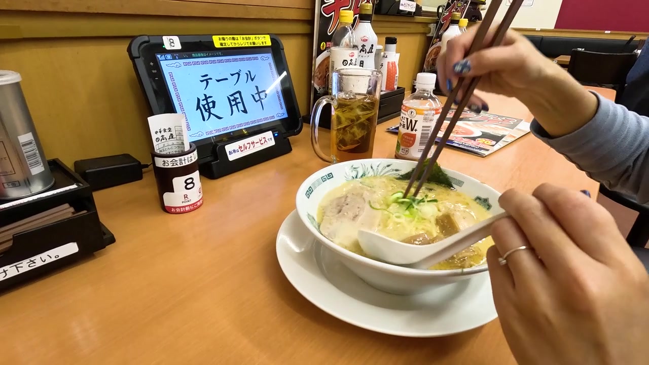 Close-up of a person using chopsticks to eat ramen at a restaurant in Tokyo.