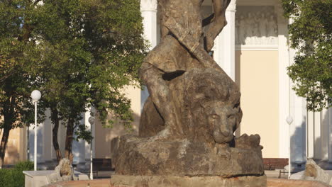 old, bronze sculpture of a defeated lion laying under the victorious hero