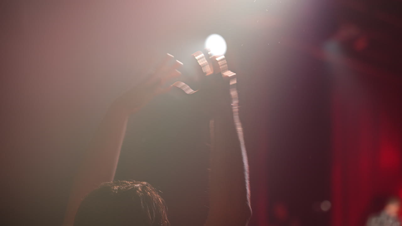 Hands raised in celebration under bright stage lights creating an energetic atmosphere