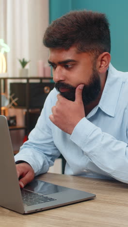indian man typing laptop stops rubs chin ponders vital idea focused creative decision moment indoors