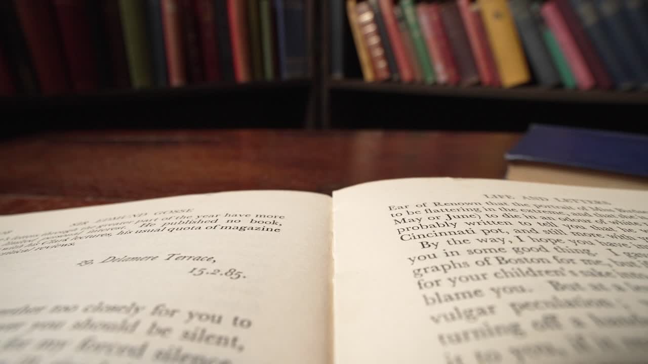 손이 페이지를 돌리는 도서관에서 책의 페이지를 가로지르는 매크로 리버스 돌리