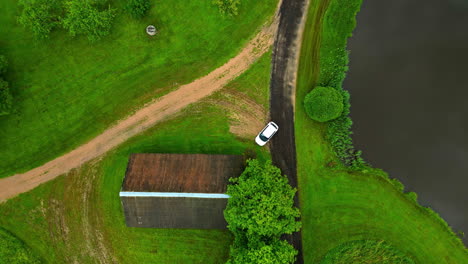 aerial view of a rural landscape with car, building, and pond