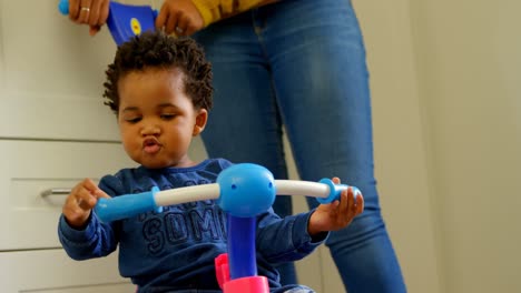 front view of cute little black son playing and sitting on tricycle in a comfortable home 4k