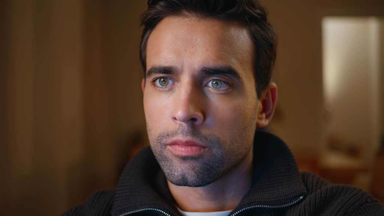 Handsome man gazing distance in dark apartment closeup. Portrait serious guy