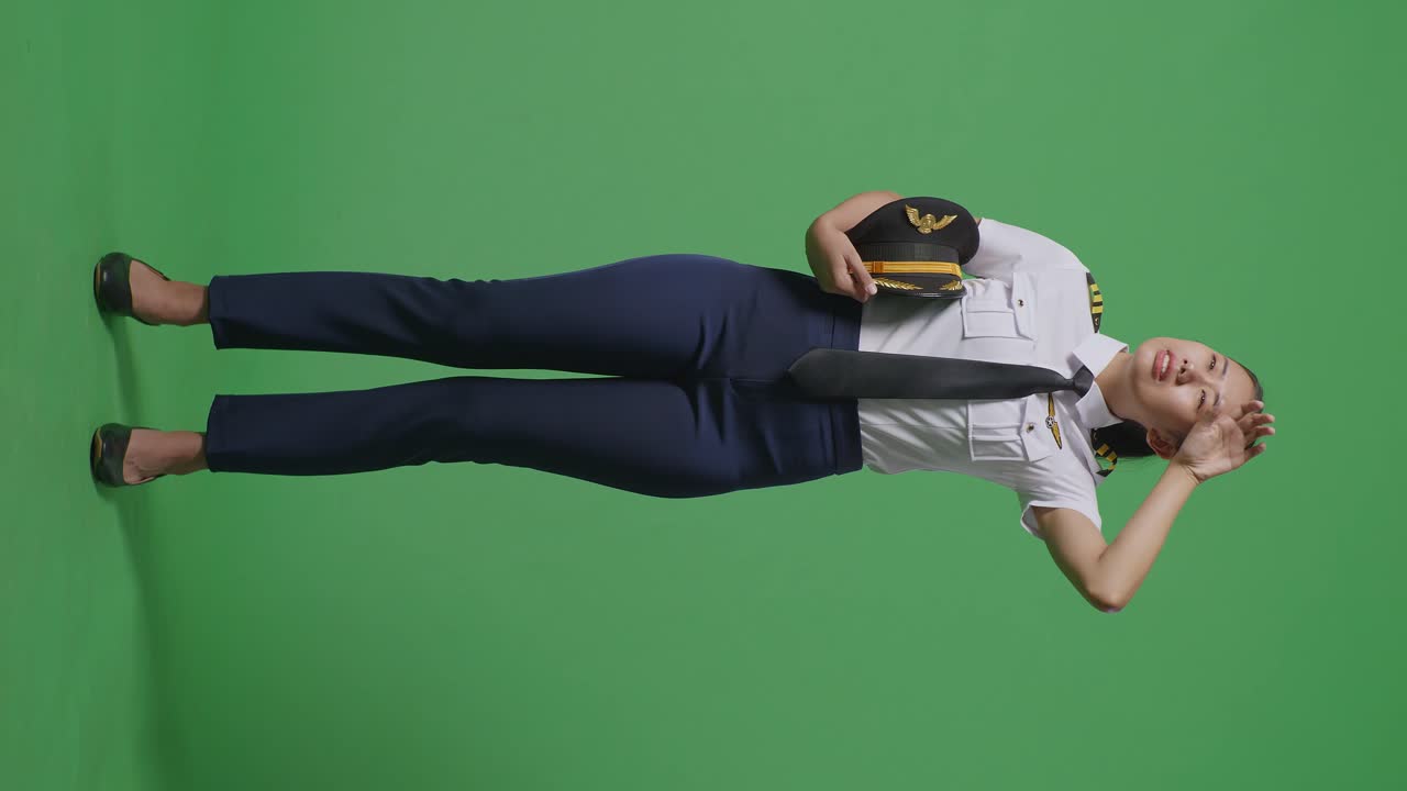 아시아 여성 조종사의 몸이 을 고 녹색 스크린 배경 스튜디오에 서있는 동안 피곤합니다.