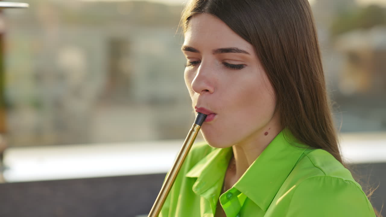 Young beautiful female producing thick white smoke from smoking nargileh. Brunette looking into camera while smoking. Close up.
