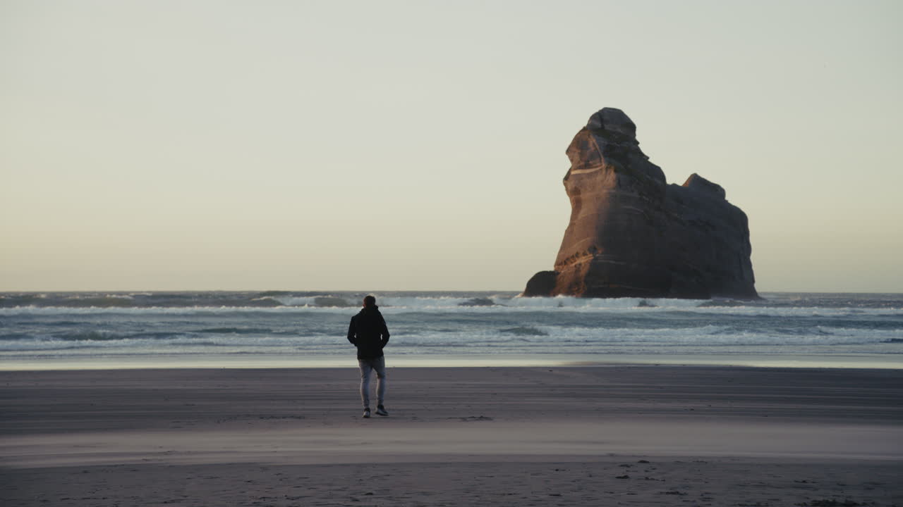 hombre caminando por la playa al atardecer