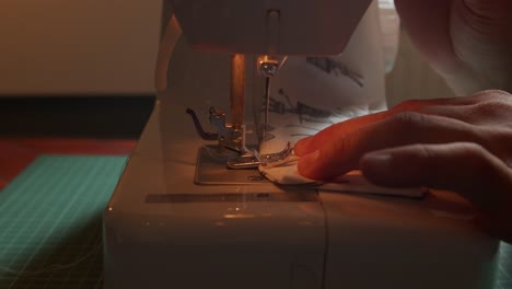 Side-slow-motion-view-of-needle-of-sewing-machine-pulling-fabric-through-guided-by-fingers