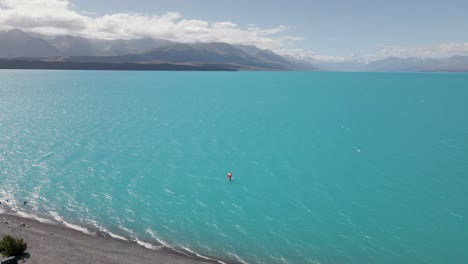 Lámina-De-Ala-Surfeando-En-El-Llamativo-Lago-Azul-Pukaki-Con-Viento-Fuerte,-Southland