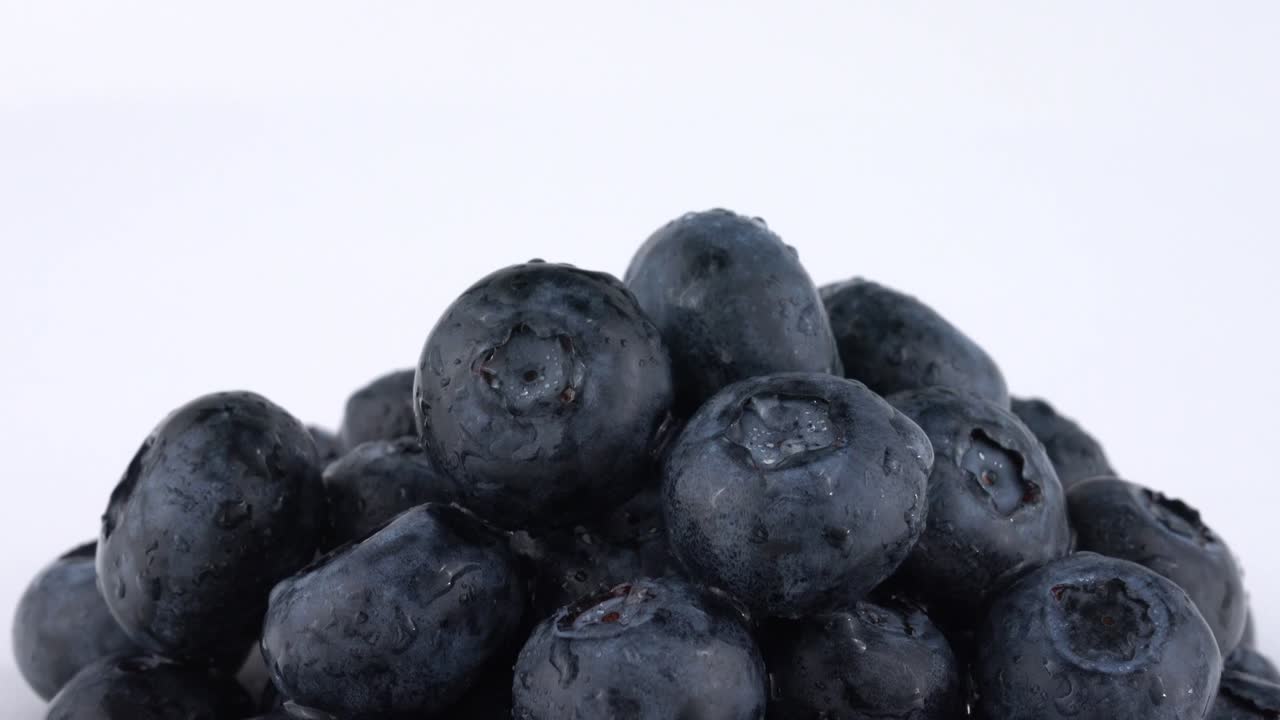색 바탕에 천천히 회전하는 신선한 블루베리 어리의 극심한 클로즈업.