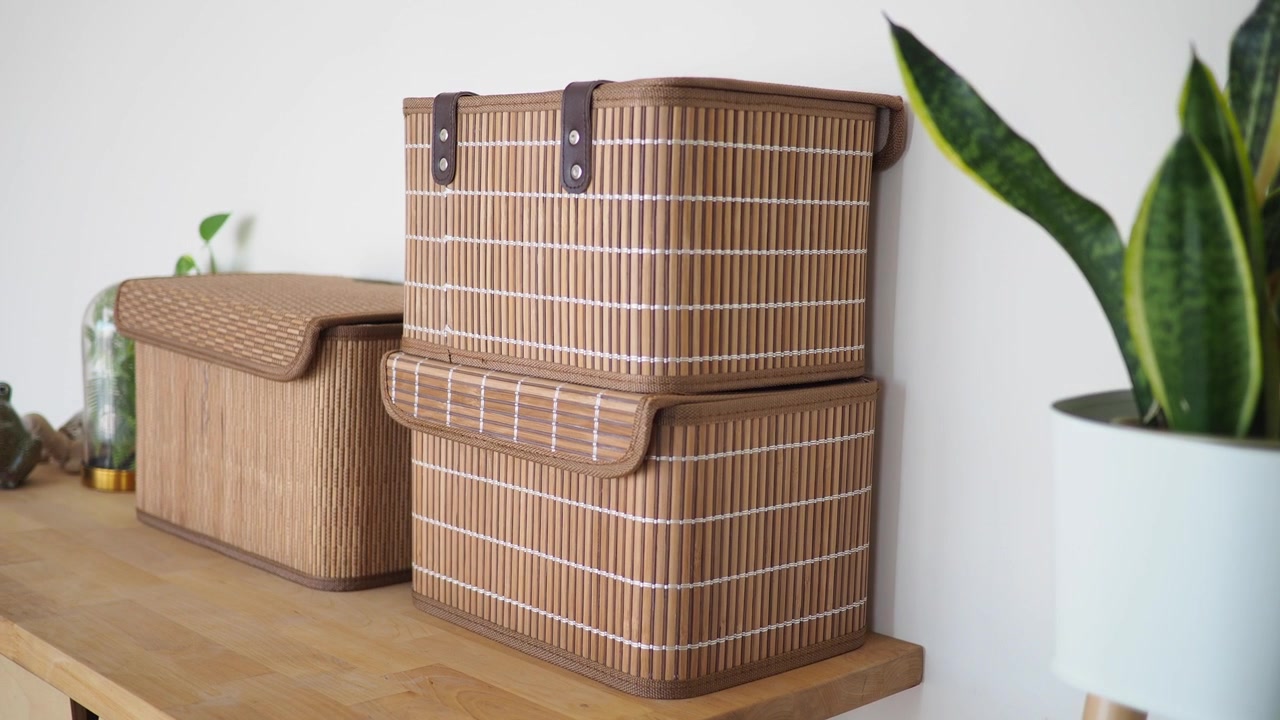 Cajas de almacenamiento de bambú apiladas en un estante de madera con una planta en maceta