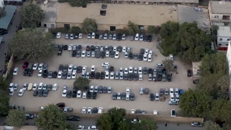 Drop-down-view-of-massive-parking-lot-full-of-cars-in-Karachi,-Pakistan