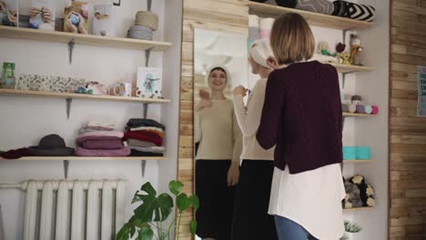 Mujer-Feliz-Colocando-Sombrero-Tejido-Espejo-Frontal-En-Taller-Textil