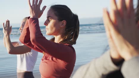 grupo de diversas amigas practicando yoga en la playa