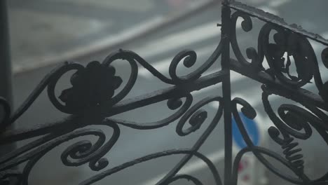 old school metal balcony railing with decoration - spirals and leaves, cars in a background