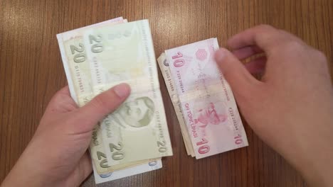a teenager counting random amount of turkish lira banknotes with portraits of famous turkish figures from science, literature and music