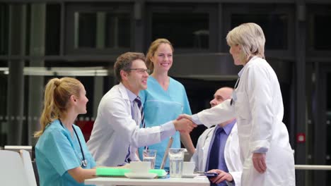 doctor shaking hands and interacting with colleagues in conference room