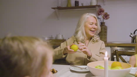 rear view of a kid sitting at table during a family dinner and talking with a mature woman