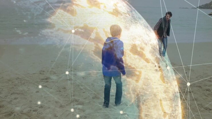 Boy approaching man on beach, kicking soccer ball and practicing, globe overlay showing tech data