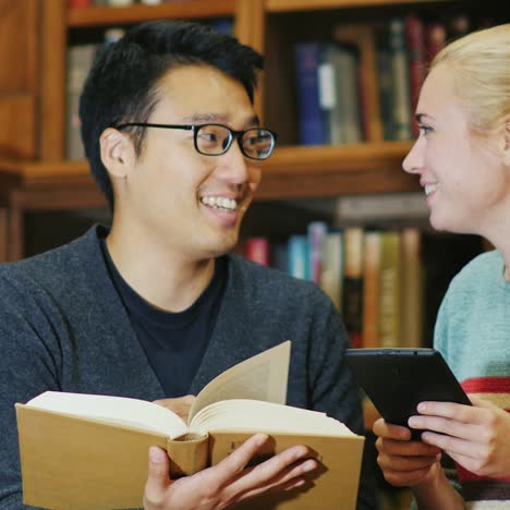 Lächelnder-Koreanischer-Mann,-Der-Mit-Einer-Frau-In-Der-Bibliothek-Spricht