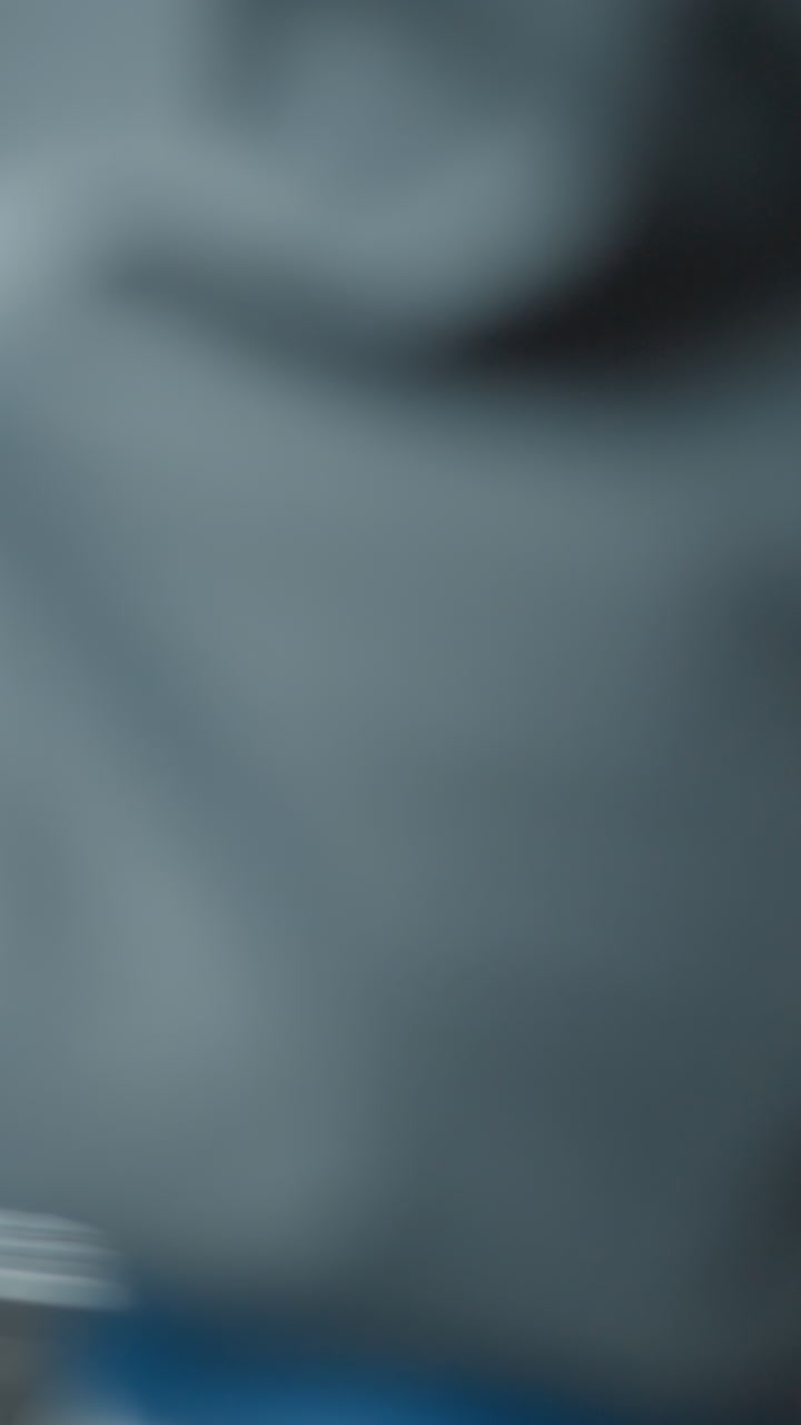 vista trasera de una mujer joven dentro de un ascensor en movimiento con iluminación natural suave que destaca el entorno urbano, los paneles de vidrio borrosos reflejan los elementos de la ciudad