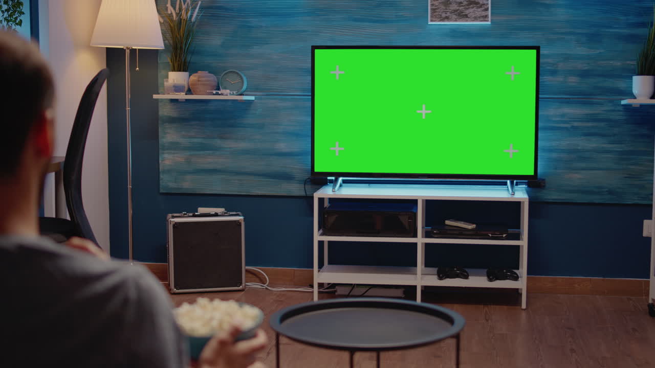Man watching green screen TV in living room