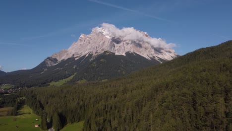 approaching drone footage of the matterhorn germanys highest mountain with woods in the foreground and blue skies and clouds