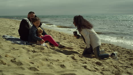 sweet family enjoy photosession on beach sand. parent kid posing picture by sea.