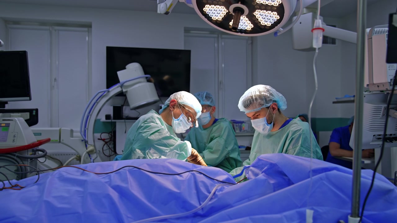 Un neurochirurgo uomo sicuro di sé utilizza le forbici durante l'intervento. L'équipe medica lavora in una moderna sala operatoria.