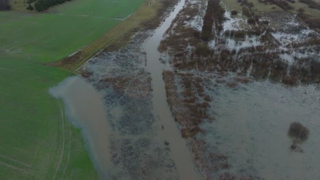 Vista-Aérea-De-La-Crecida-Del-Agua-En-Primavera,-Inundación-Del-Río-Alande,-Agua-Marrón-Y-Fangosa,-Campos-Agrícolas-Bajo-El-Agua,-Día-Nublado,-Amplio-Disparo-De-Drones-Avanzando-Inclinado-Hacia-Abajo