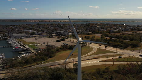 counterclockwise-drone-shot-orbiting-around-a-white-wind-turbine-with-the-glistening-Atlantic-Ocean-in-the-background-near-Point-Lookout,-NY