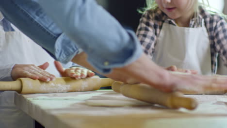 children of elementary school age kneading dough together and enjoying cooking in kitchen