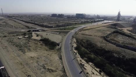 una vista aérea en cámara lenta de una carretera y una ciudad, los arrastreros pesados y los coches se mueven por la carretera, se conecta un intercambio