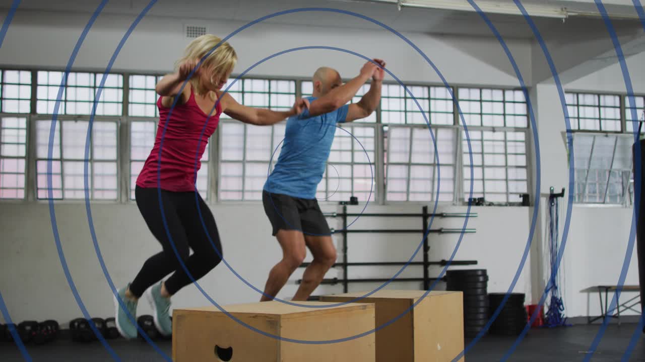 Workout partners initiating squat on wooden boxes, jumping down, rebounding for fitness training