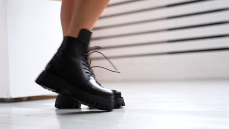 unrecognized lady with bare legs wearing stylish fashionable boots on tractor soles. footwear demonstration in studio. close up.