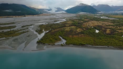 River-delta-on-edge-of-calm-placid-Lake-Wakatipu,-panoramic-establishing-overview