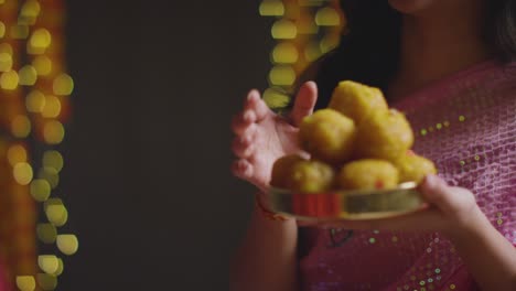 close up of woman giving ladoo to man to eat celebrating festival of diwali