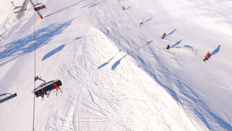 an aerial shot passing over skiers on a ski slope and in a chairlift in les deux alpes in the french alps