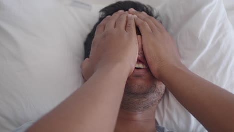 man covering face in bed