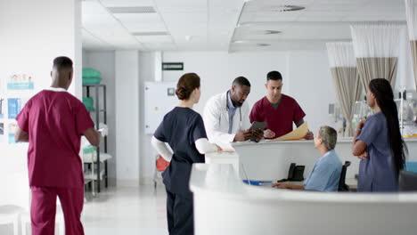 Verschiedene-Ärzte-Besprechen-Ihre-Arbeit,-Benutzen-Ein-Tablet-An-Der-Rezeption-Im-Krankenhaus,-Zeitlupe