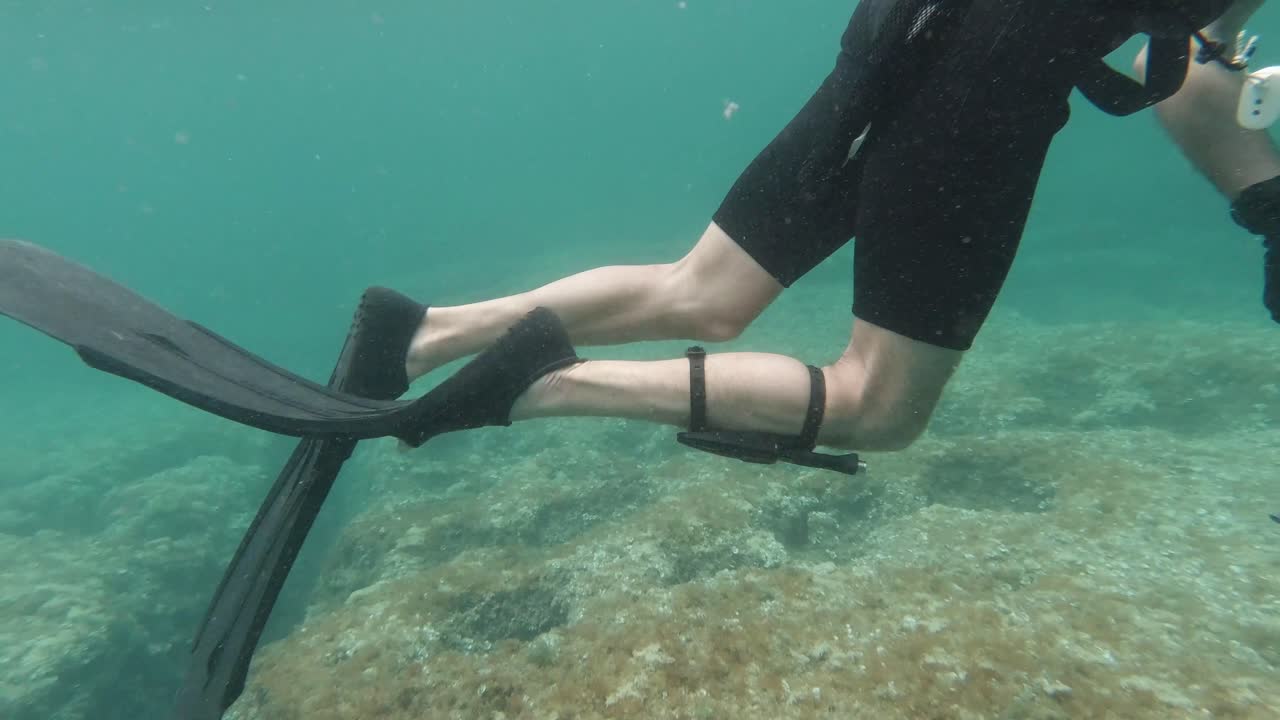 Detail shot of spearfisher fins, harpoon and dive knife in the mediterranean sea in slow motion