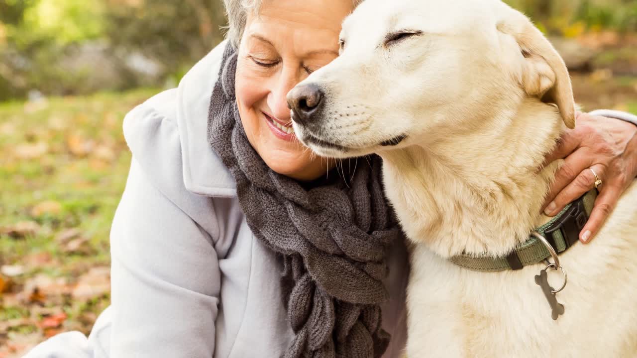 mujer mayor caucásica feliz abrazando a un perro mascota golden retriever en el parque