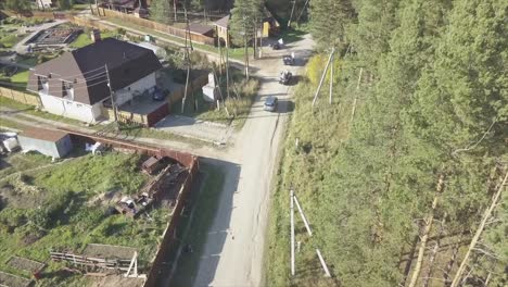 aerial view of a rural road with houses and cars in a forest