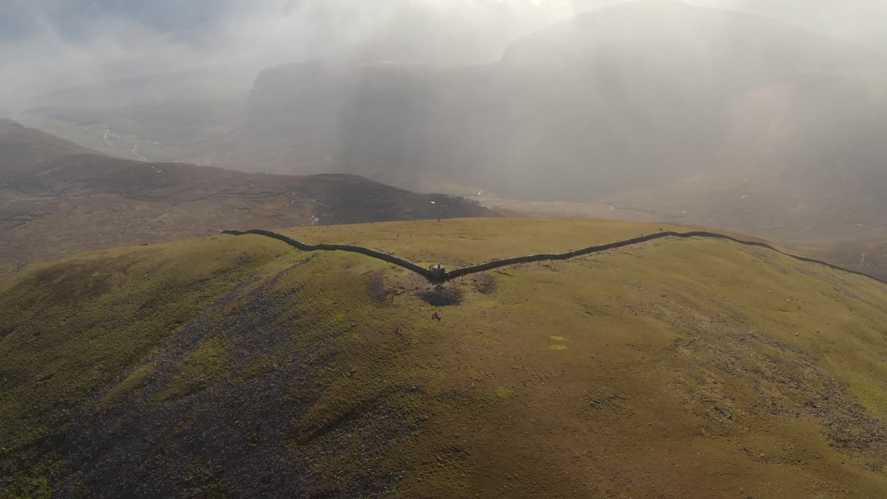 Aerial through dense clouds reveals Slieve Donard's peak