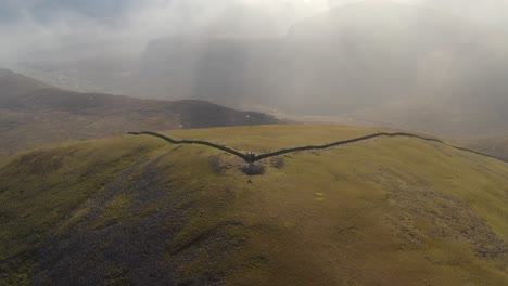 Aerial through dense clouds reveals Slieve Donard&#039;s peak